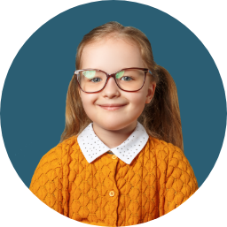 Young girl with glasses in a yellow sweater smiles into the camera.